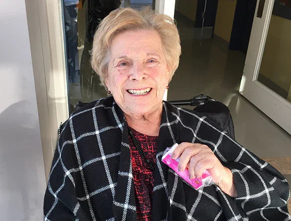 Smiling senior woman in a wheelchair wearing adaptive checkered clothing indoors