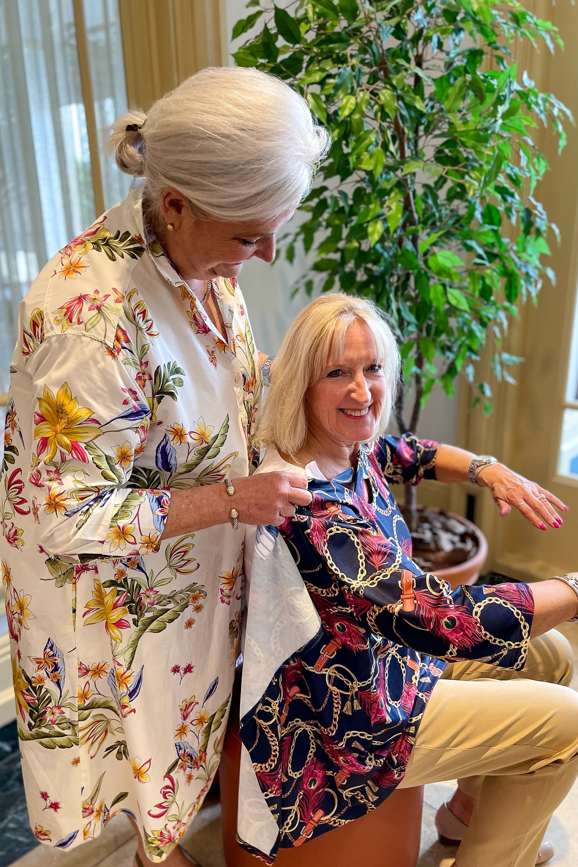 Senior woman assisting another woman with easy dressing adaptive clothing indoors