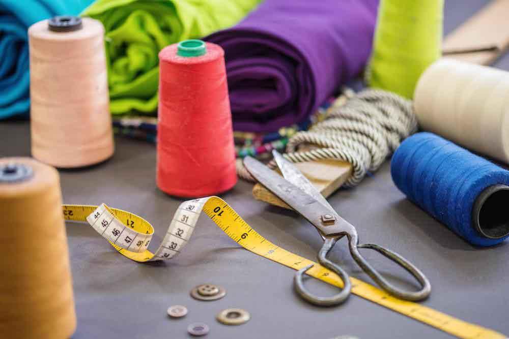 Colorful sewing supplies with fabric, thread spools, scissors, and measuring tape for adaptive clothing