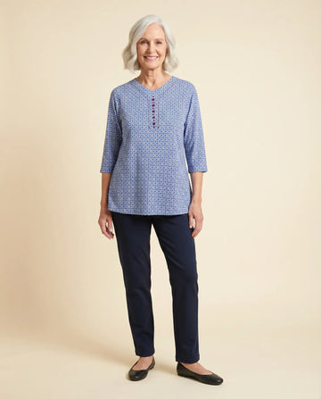 Senior woman wearing Ovidis adaptive blue daisy print top with burgundy button detail, easy dressing