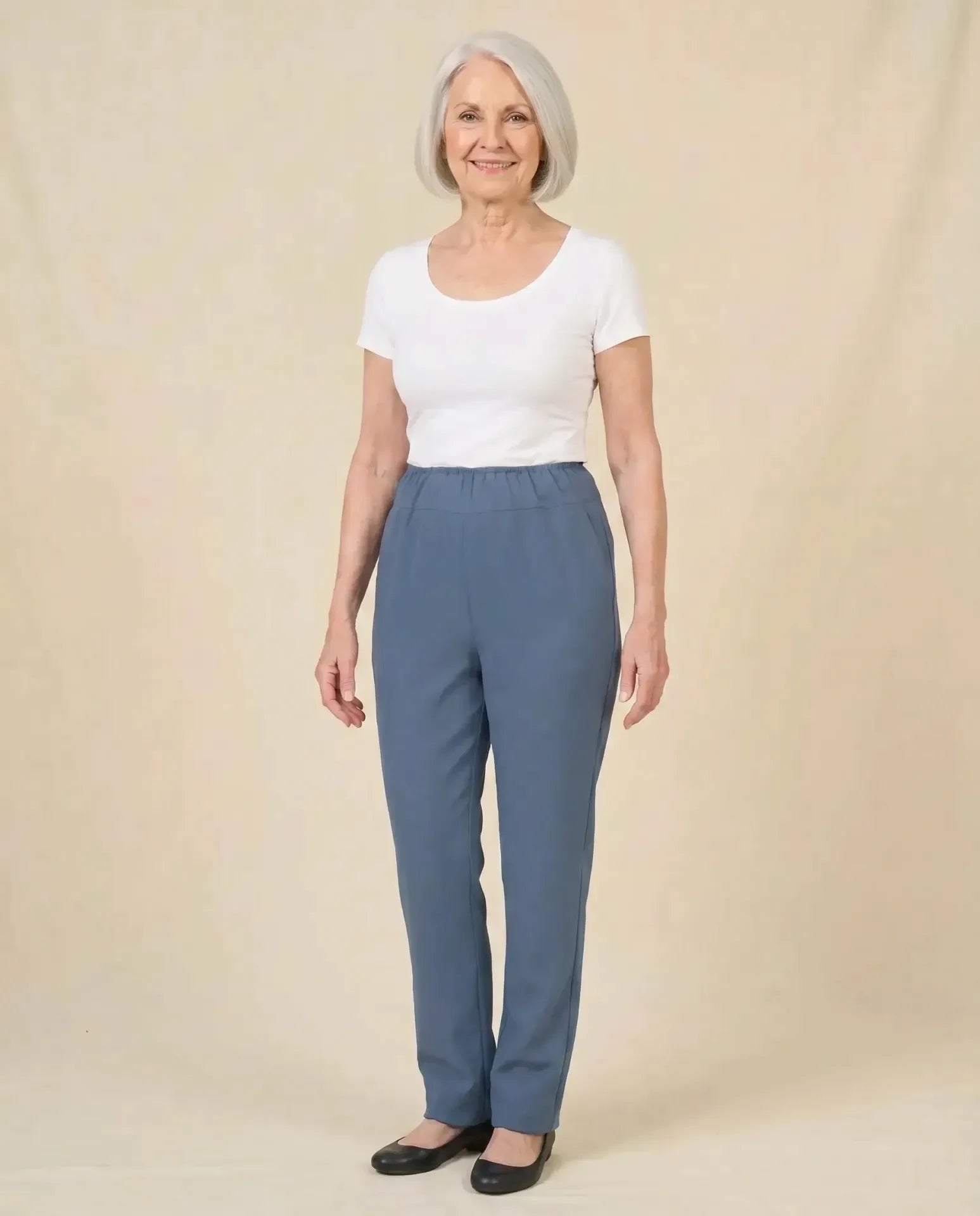 Senior woman wearing Ovidis Sara Pants in Blue, full body front view on parchment backdrop