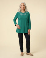 Senior woman wearing Ovidis adaptive deep teal green top with paisley embroidery neckline, easy dressing