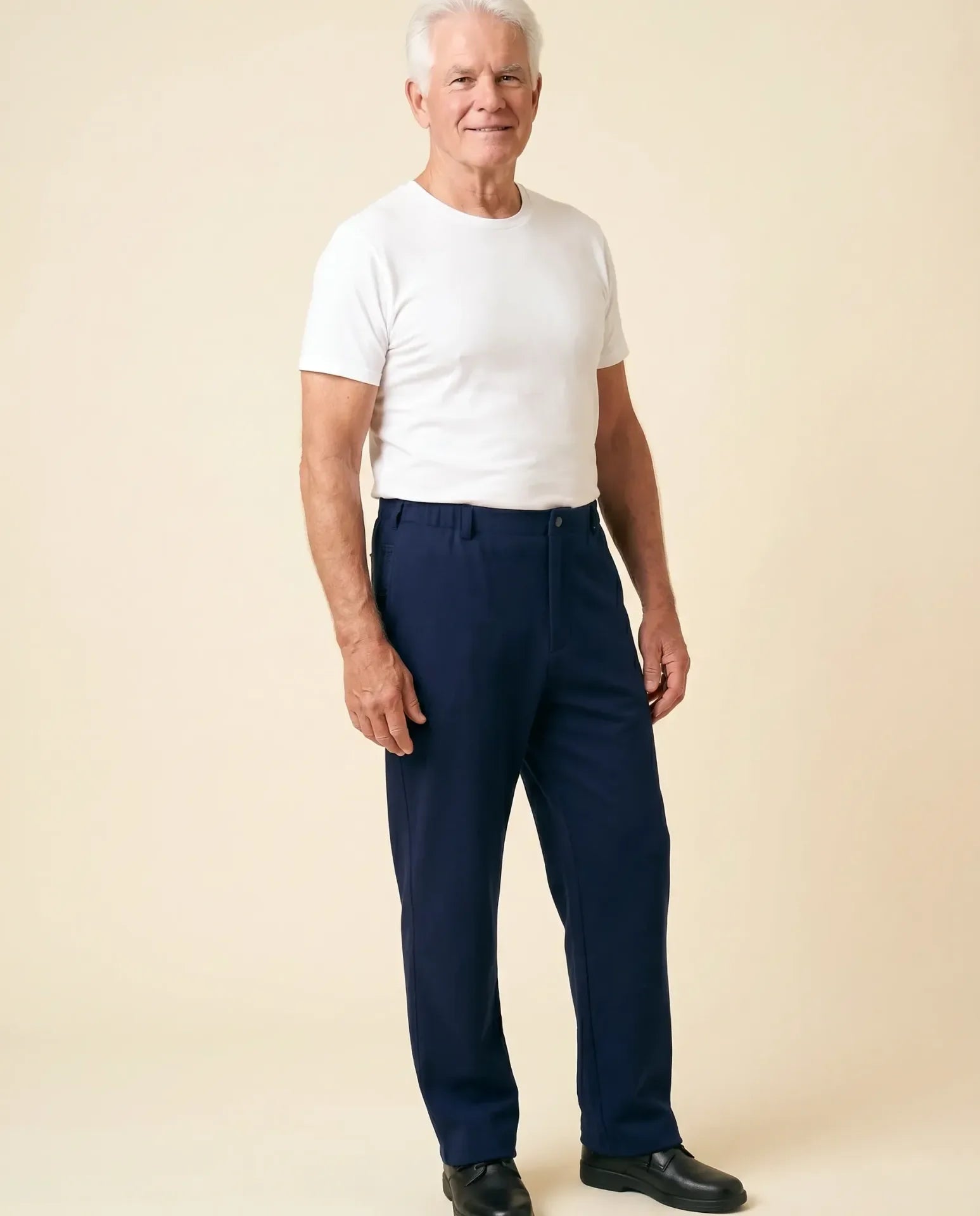Senior man wearing Ovidis Stan Pants in Navy, full body front view on parchment backdrop