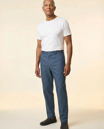 Senior man wearing Ovidis Liam Jeans in Blue, full body front view on parchment backdrop
