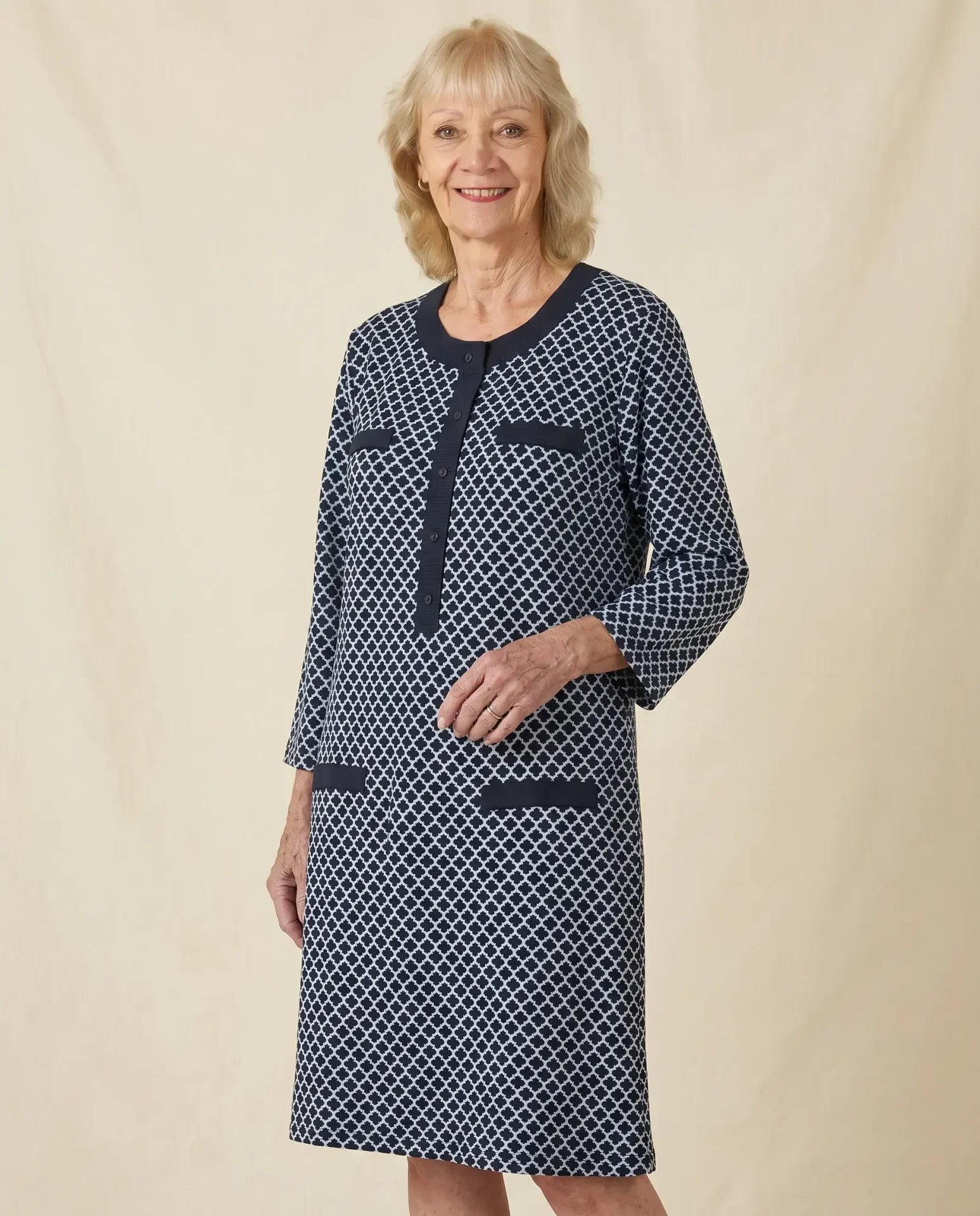 Senior white woman wearing Vera Blue adaptive jacquard dress with ribbed trim, parchment backdrop
