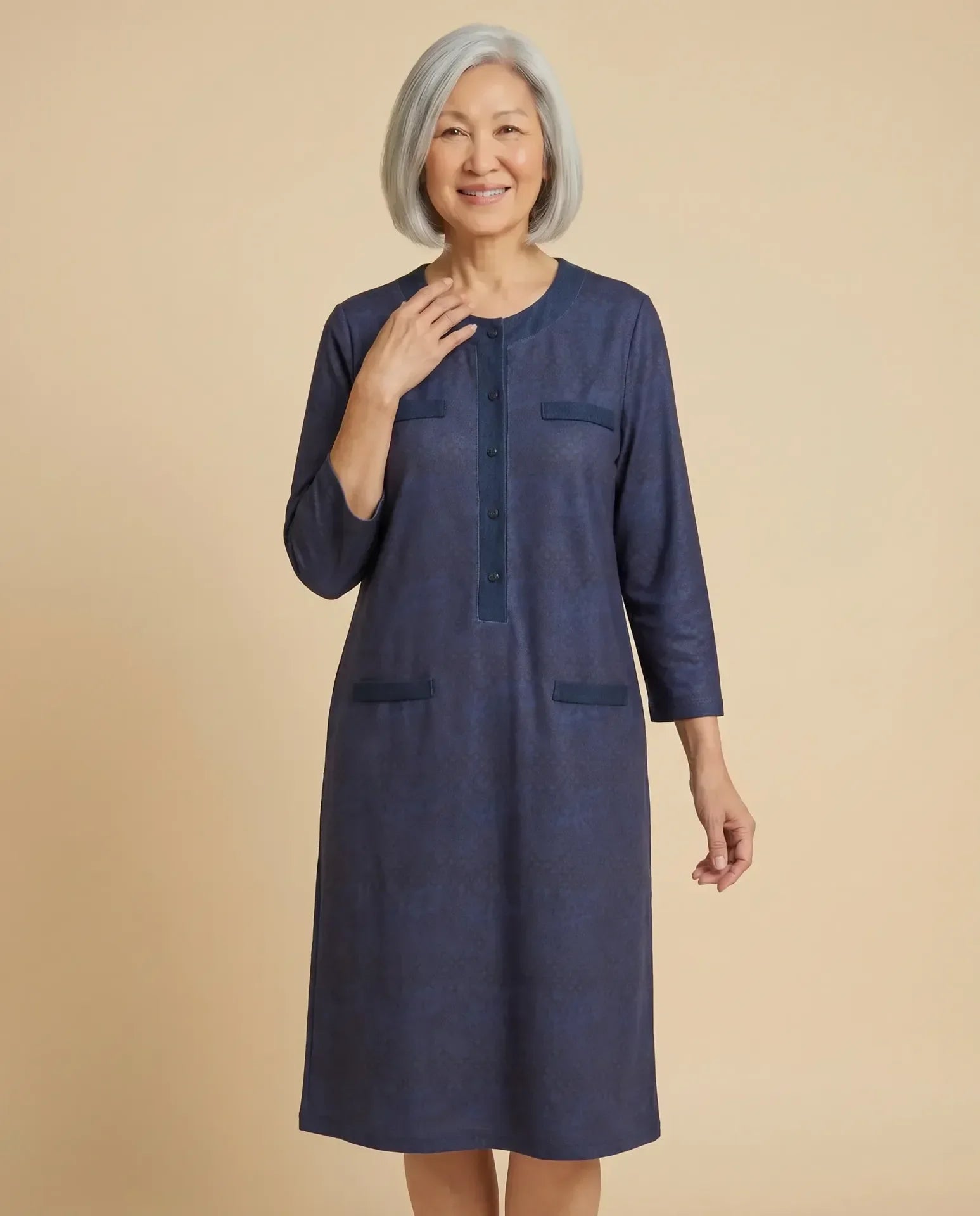 Senior Asian woman wearing Vera Moonlight adaptive navy dress with denim trim, parchment backdrop