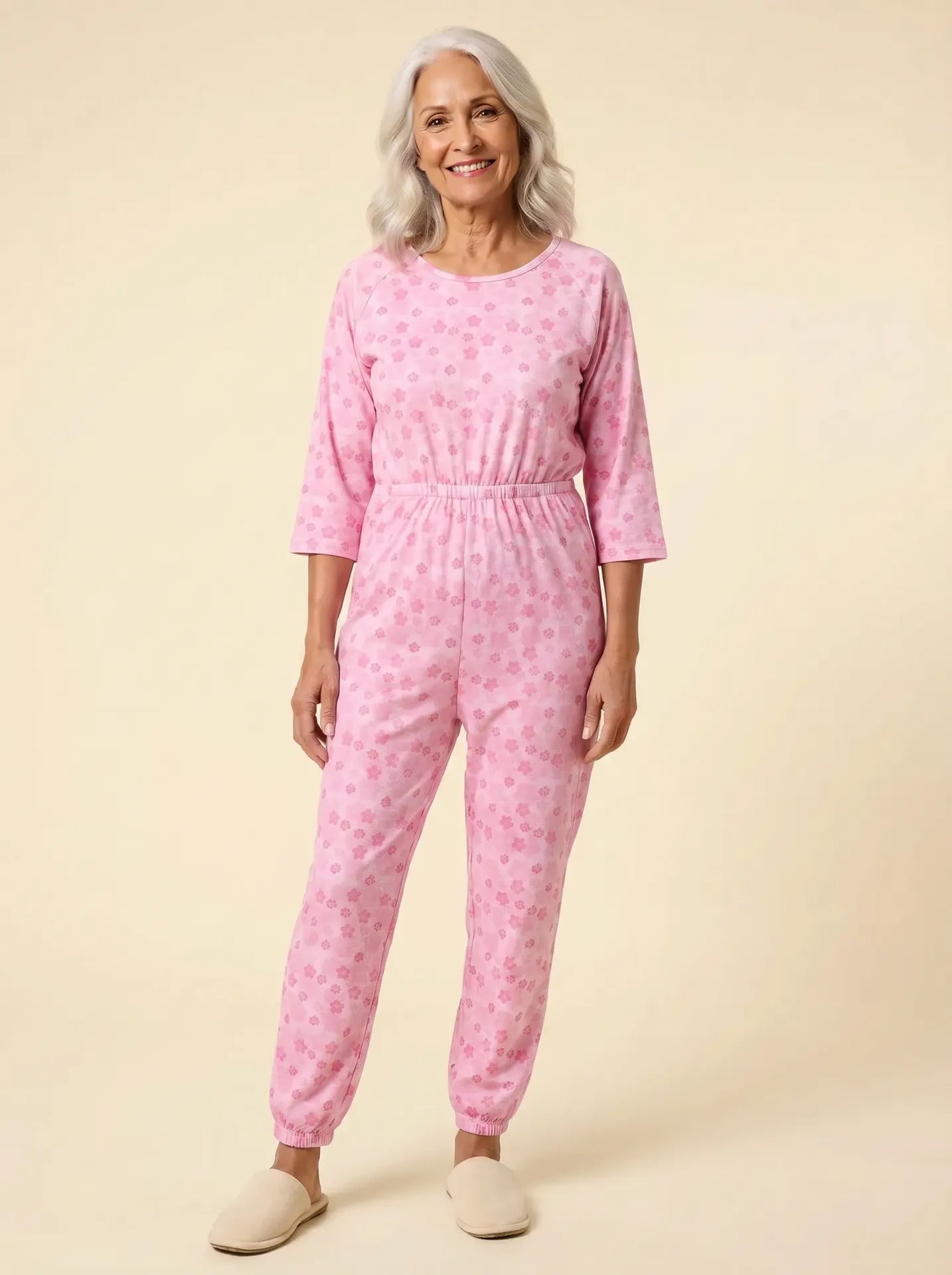 Senior woman wearing Ovidis adaptive orchid floral jumpsuit, front view, warm studio lighting