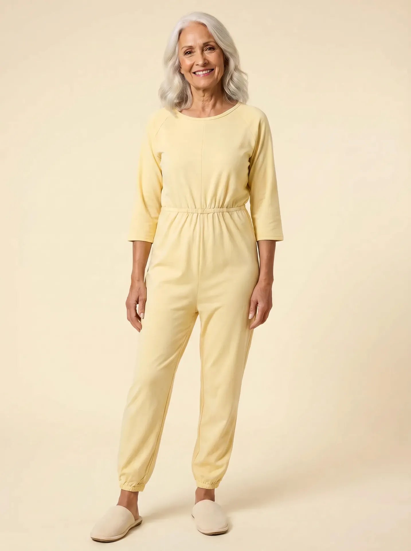 Senior woman wearing Ovidis adaptive yellow jumpsuit, front view, warm studio lighting