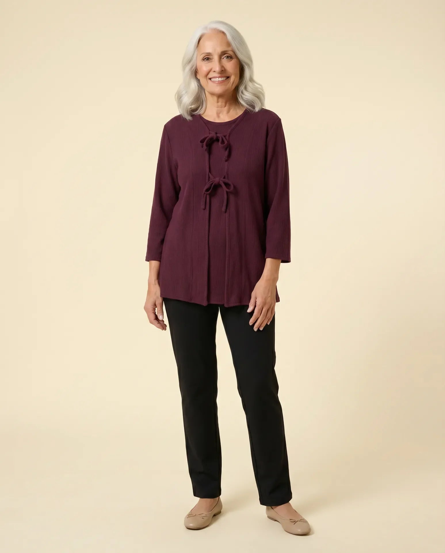 Senior woman wearing adaptive burgundy cable-knit top with front self-tie closures, paired with black pants