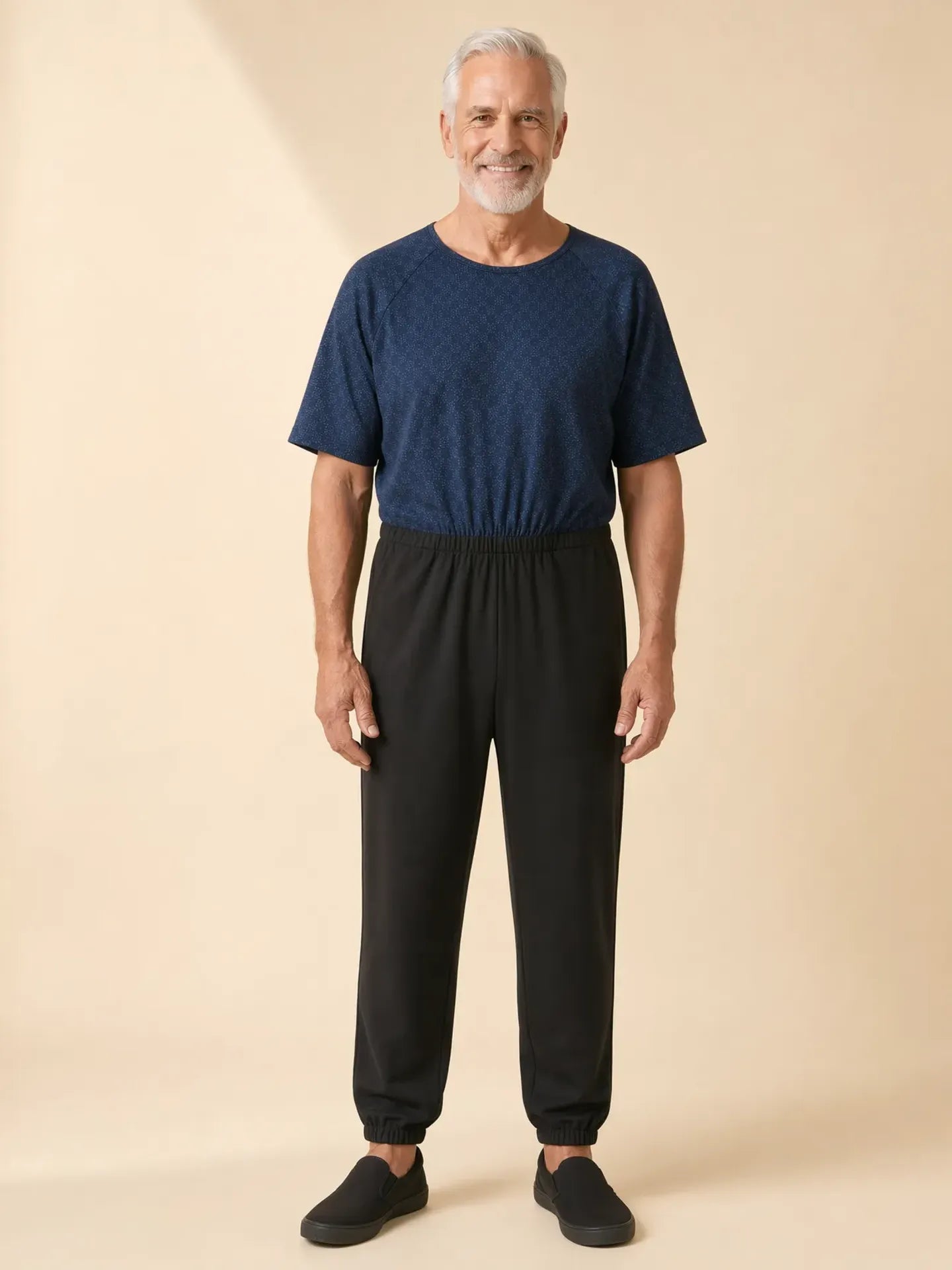 Senior man wearing Ovidis adaptive Bobby Starlight jumpsuit, front view, warm studio lighting