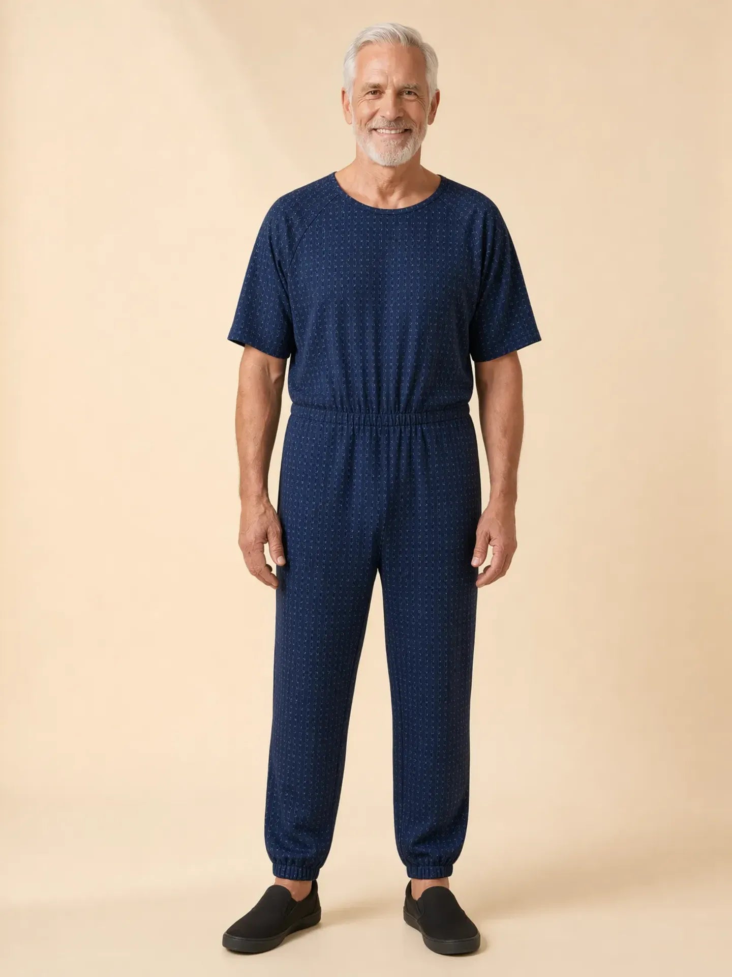 Senior man wearing Ovidis adaptive Bobby Twilight jumpsuit, front view, warm studio lighting