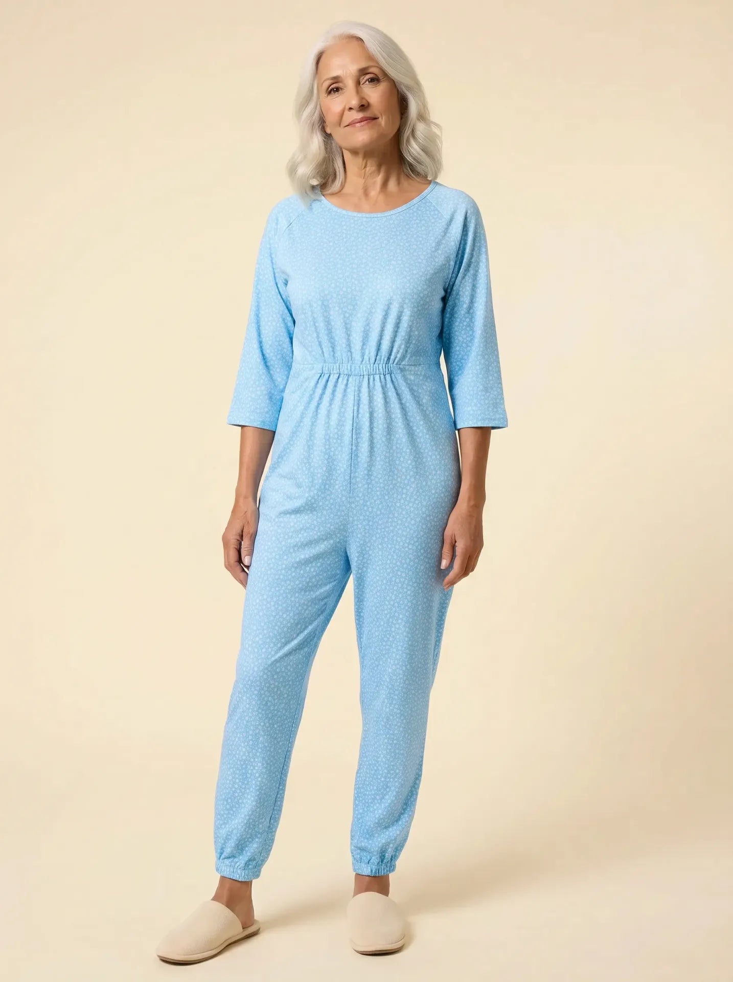 Senior woman wearing Ovidis adaptive sky blue dot jumpsuit, front view, warm studio lighting