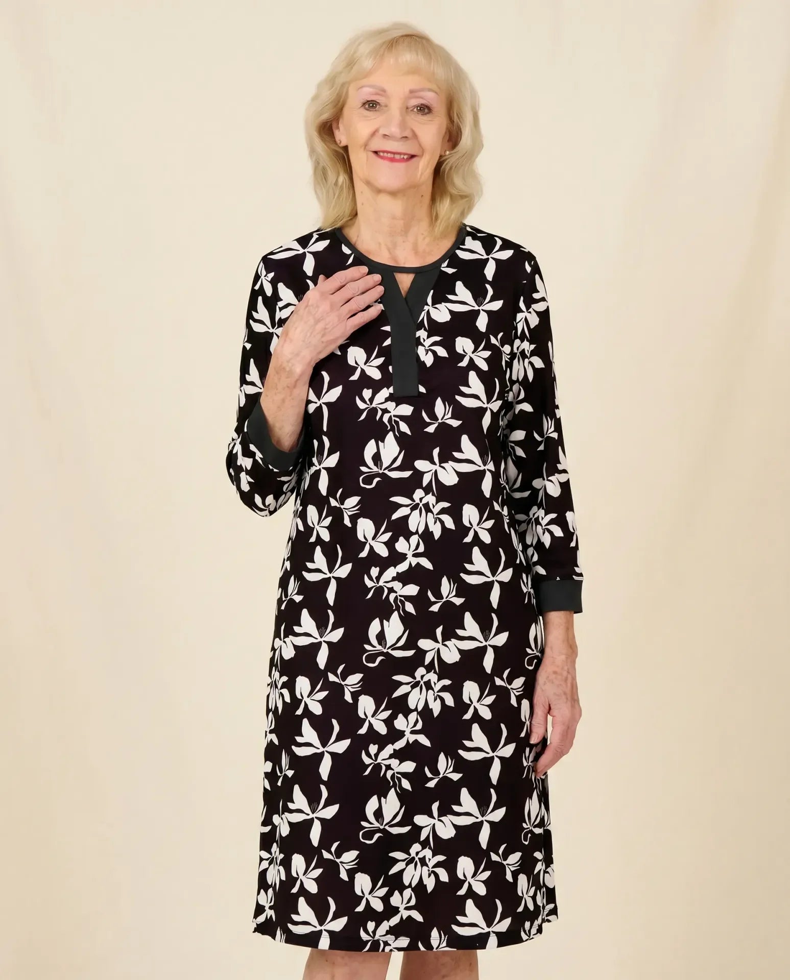Senior white woman wearing Lisa Black adaptive floral dress with keyhole neckline, parchment backdrop