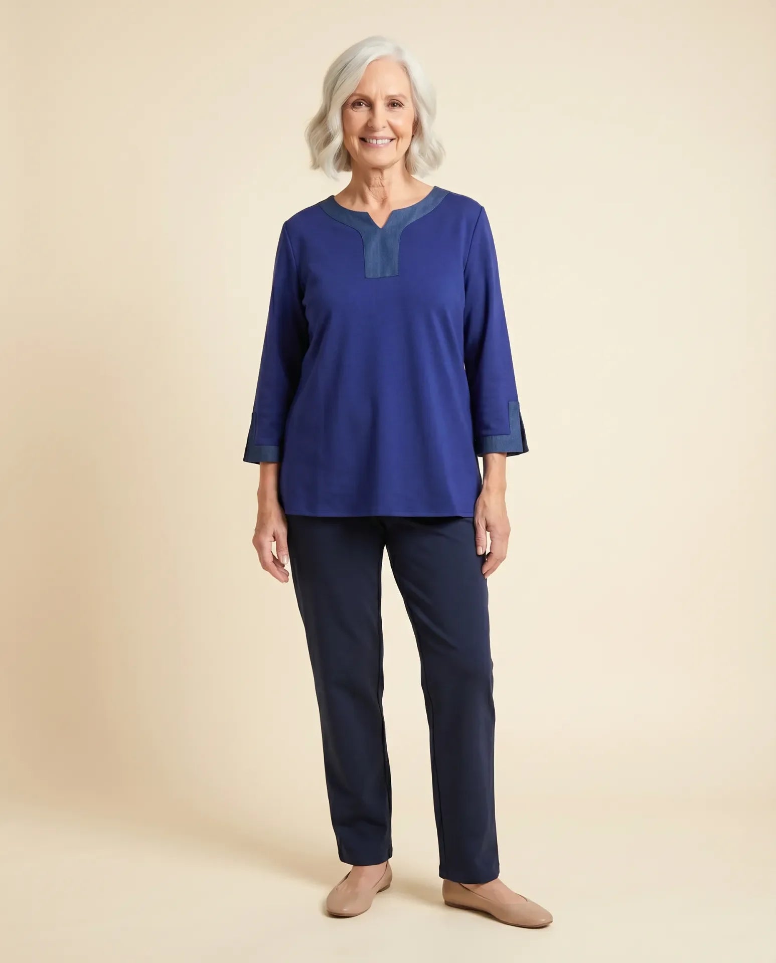 Senior woman wearing adaptive indigo blue top with contrast denim V-neckline and sleeve cuff trim, paired with navy pants