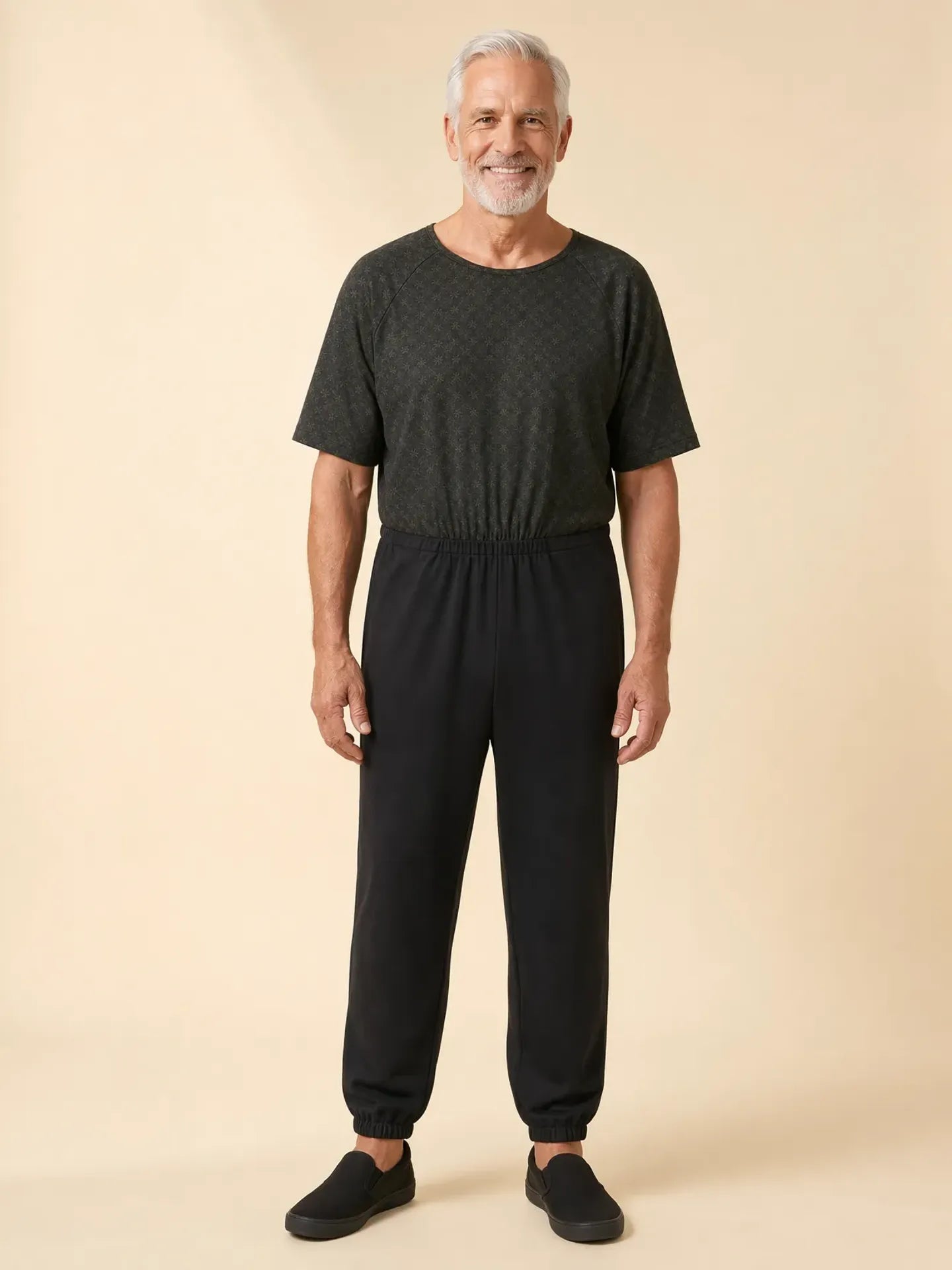 Senior man wearing Ovidis adaptive Bobby Trellis jumpsuit, front view, warm studio lighting