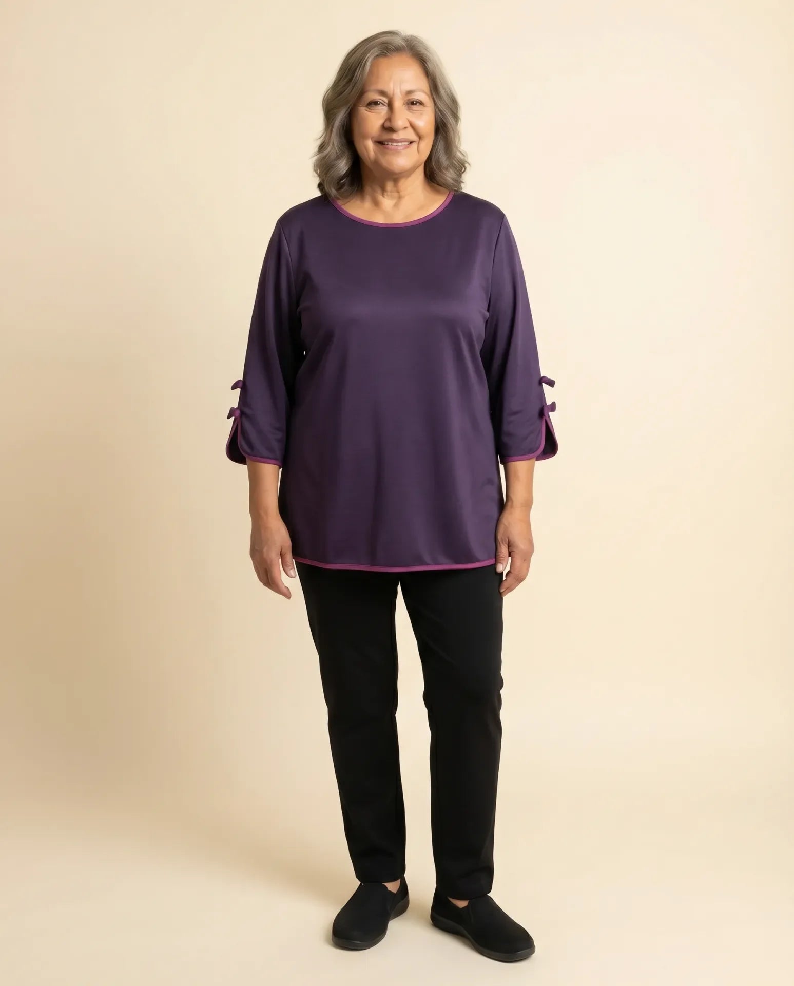 Senior woman wearing adaptive deep plum satin-effect top with sleeve bow-knot details and magenta piping trim