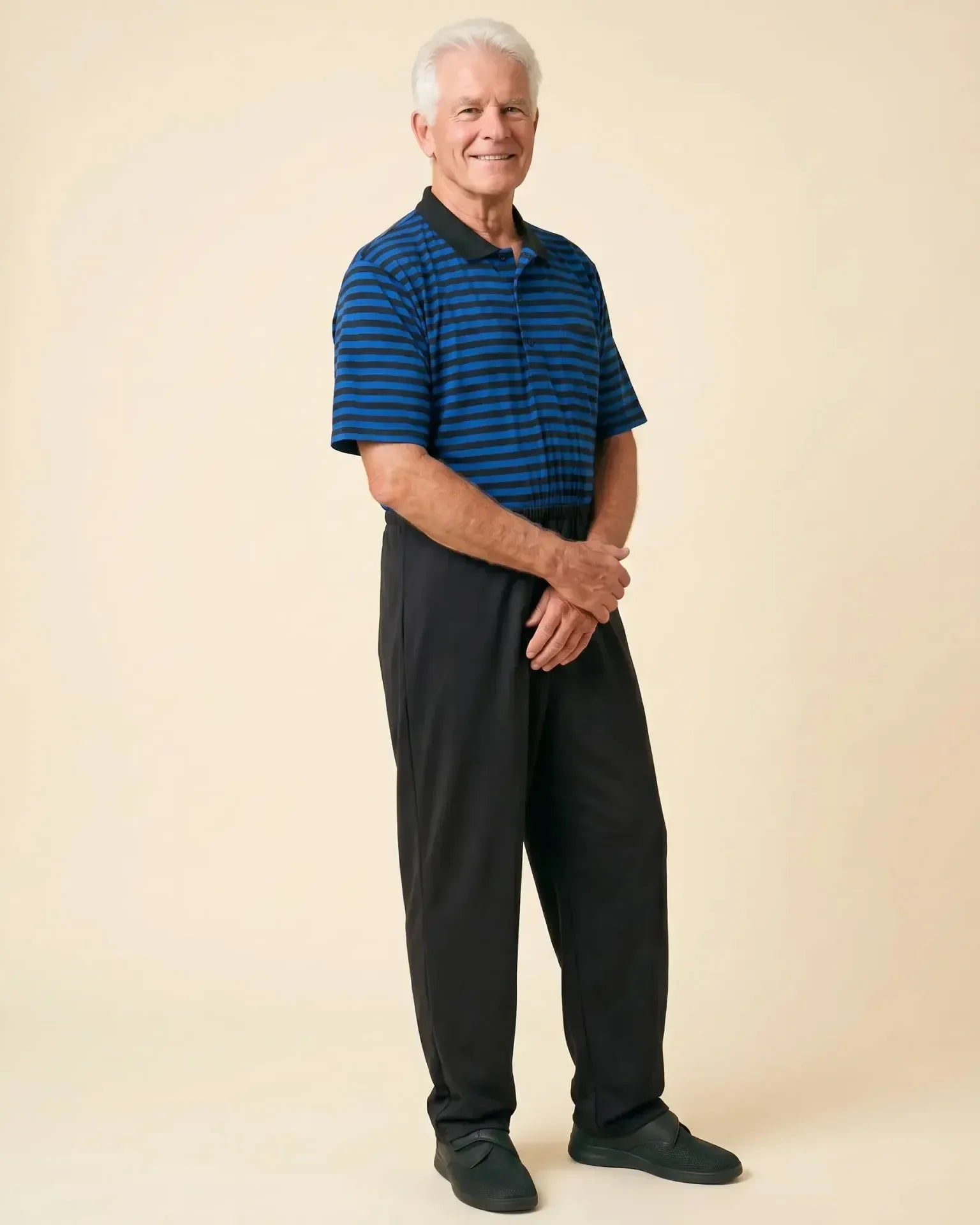 Senior man wearing Charly Blue adaptive jumpsuit — royal blue and black stripe polo top with black pants