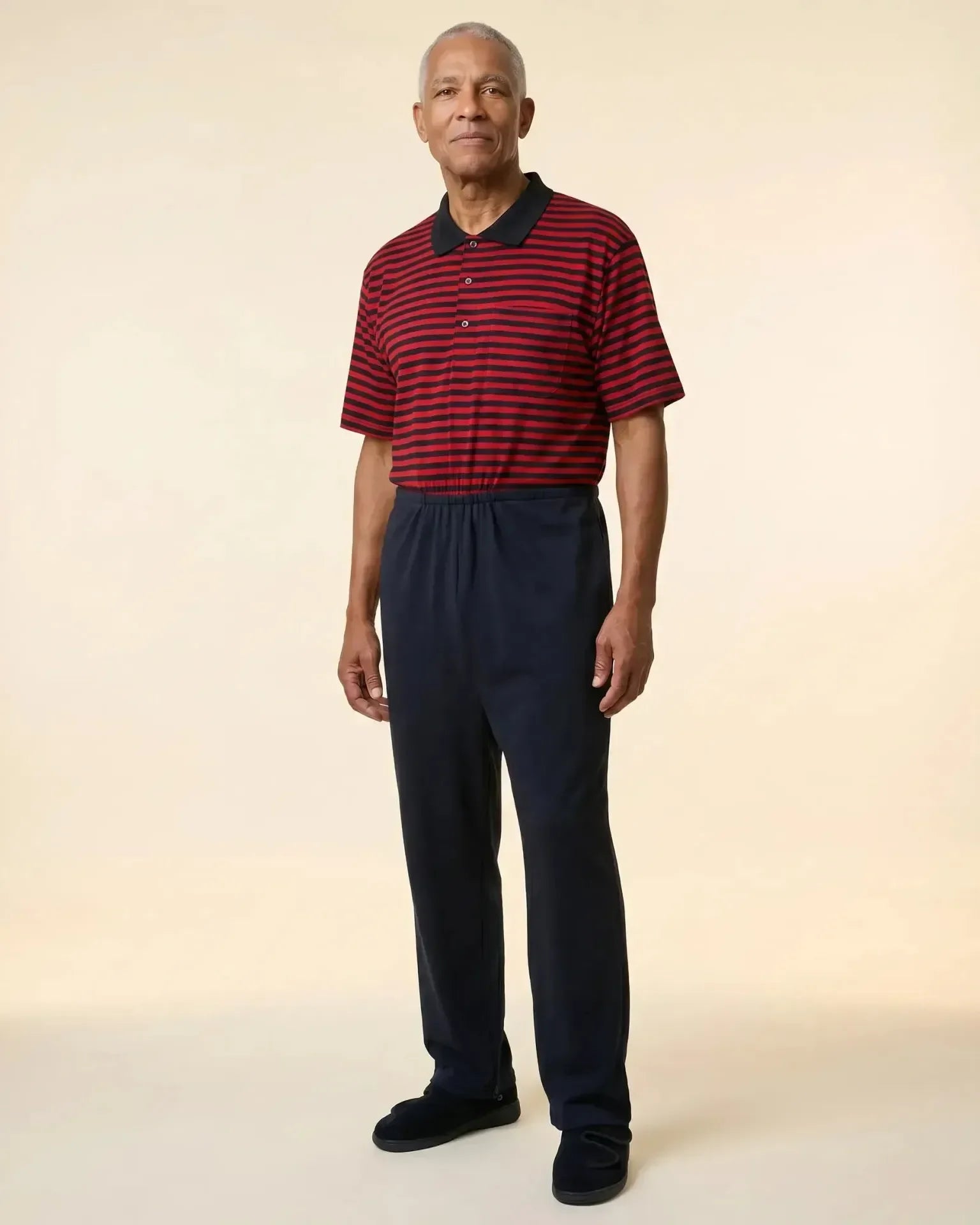 Senior man wearing Charly Red adaptive jumpsuit — red and black stripe polo top with dark navy pants