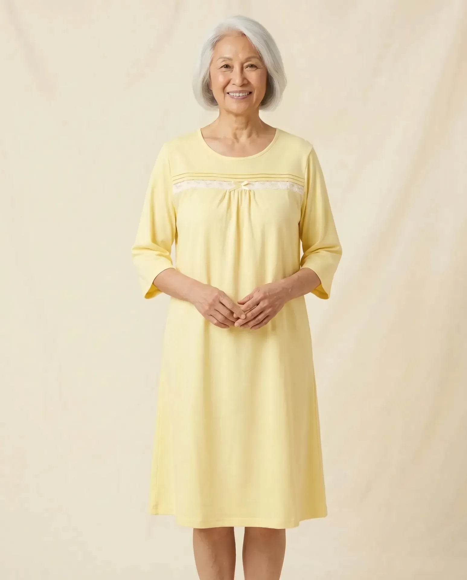 Senior woman wearing Olivia Nightgown in Honeysuckle, clasped hands pose, parchment backdrop