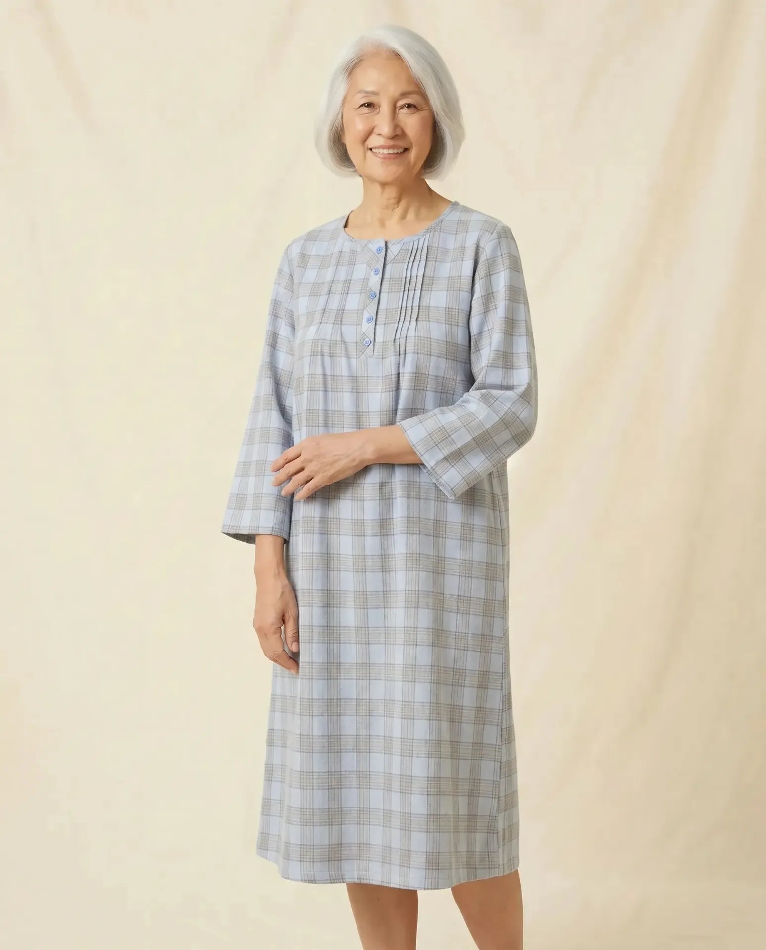 Senior woman wearing Elsa Nightgown in Blue plaid, open arm pose, parchment backdrop