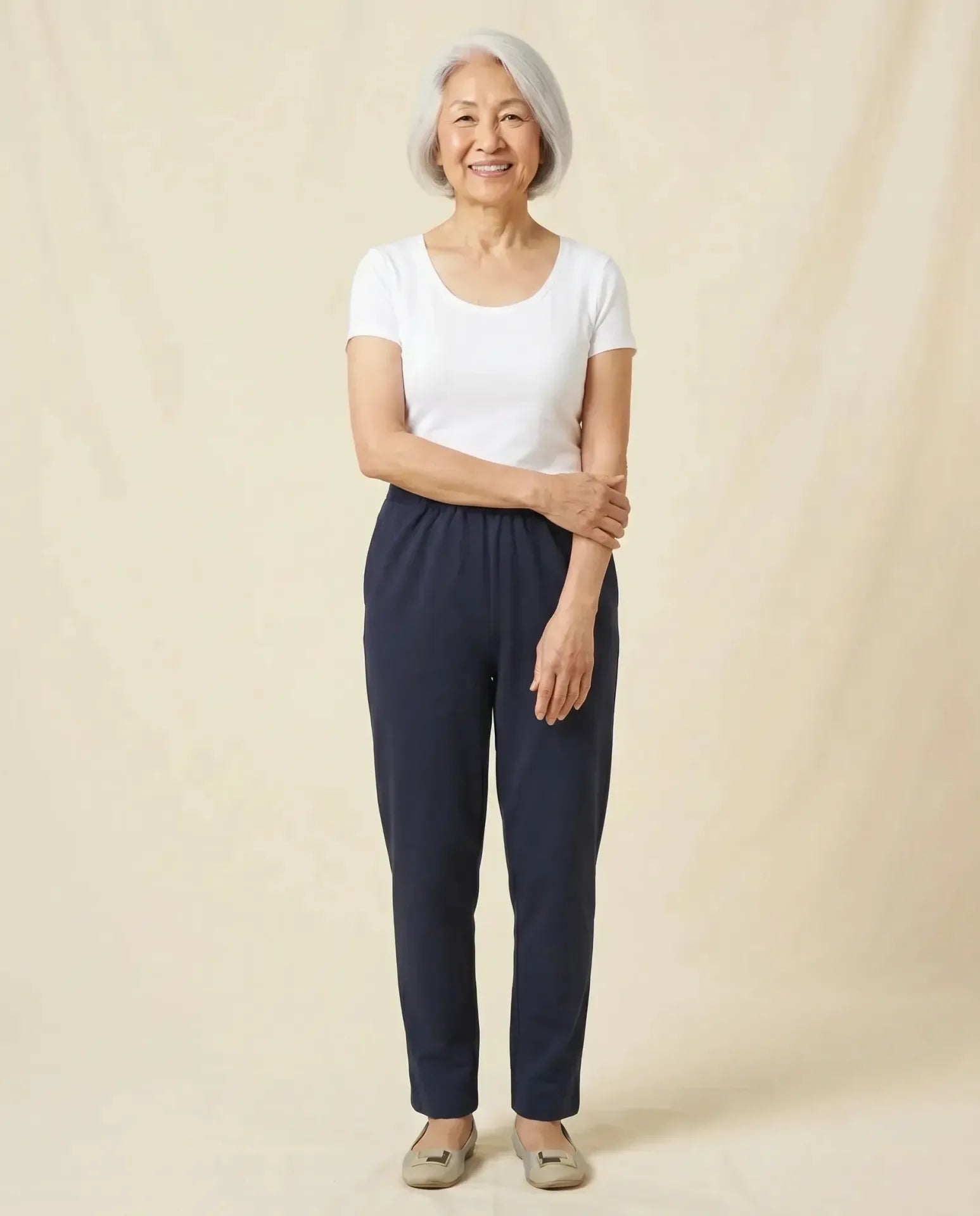 Senior Asian woman wearing Ovidis Arie Pants in Navy, full body front view on parchment backdrop