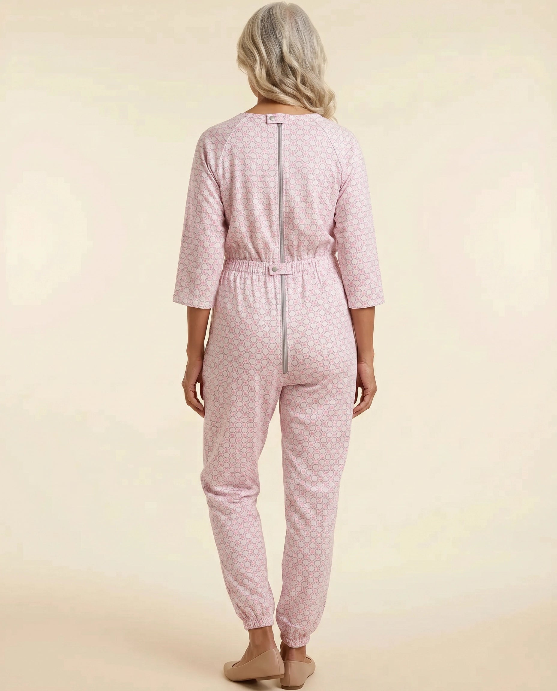 Senior woman wearing Ovidis adaptive Carrie Blush geometric jumpsuit, full body back view showing center-back zipper and snap closures