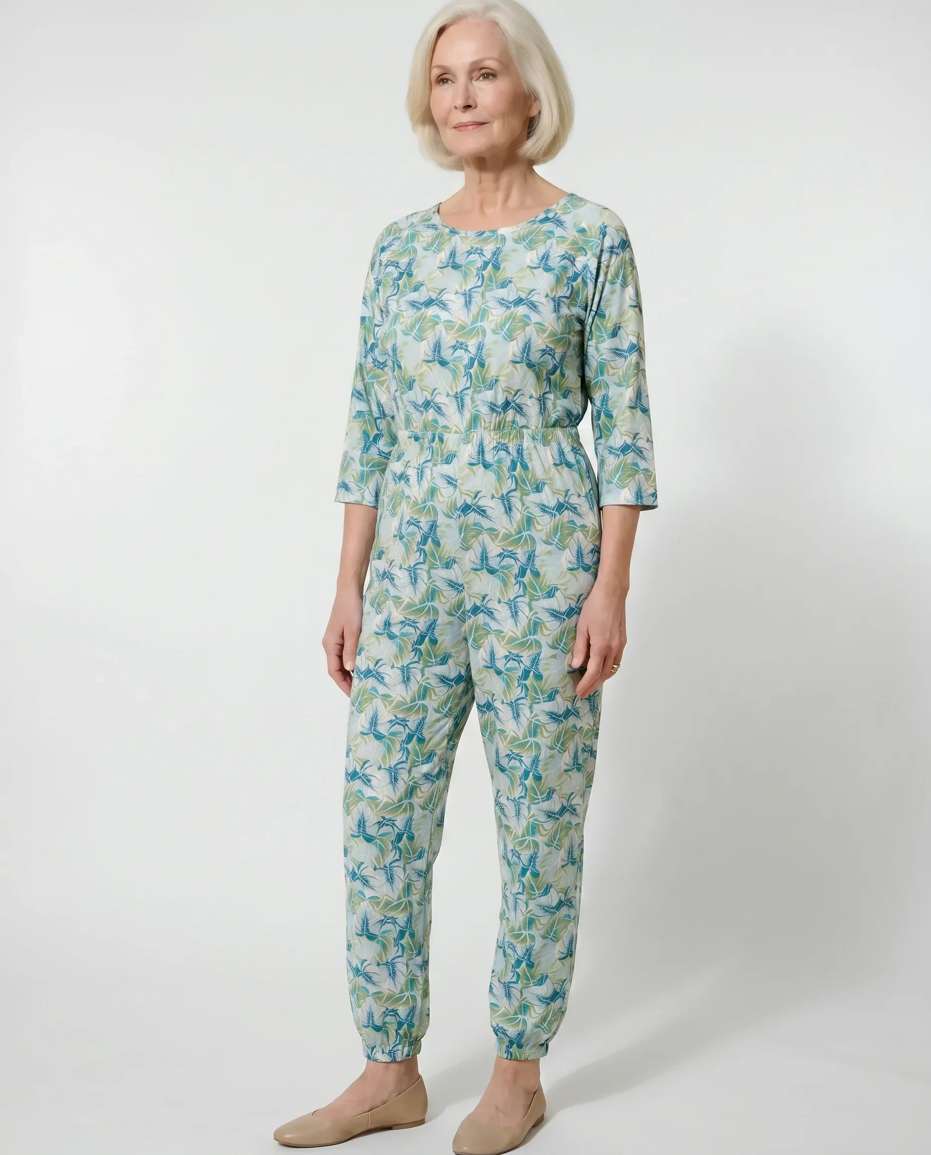 Senior woman wearing Ovidis adaptive Carrie Mint tropical leaf jumpsuit, full body front view