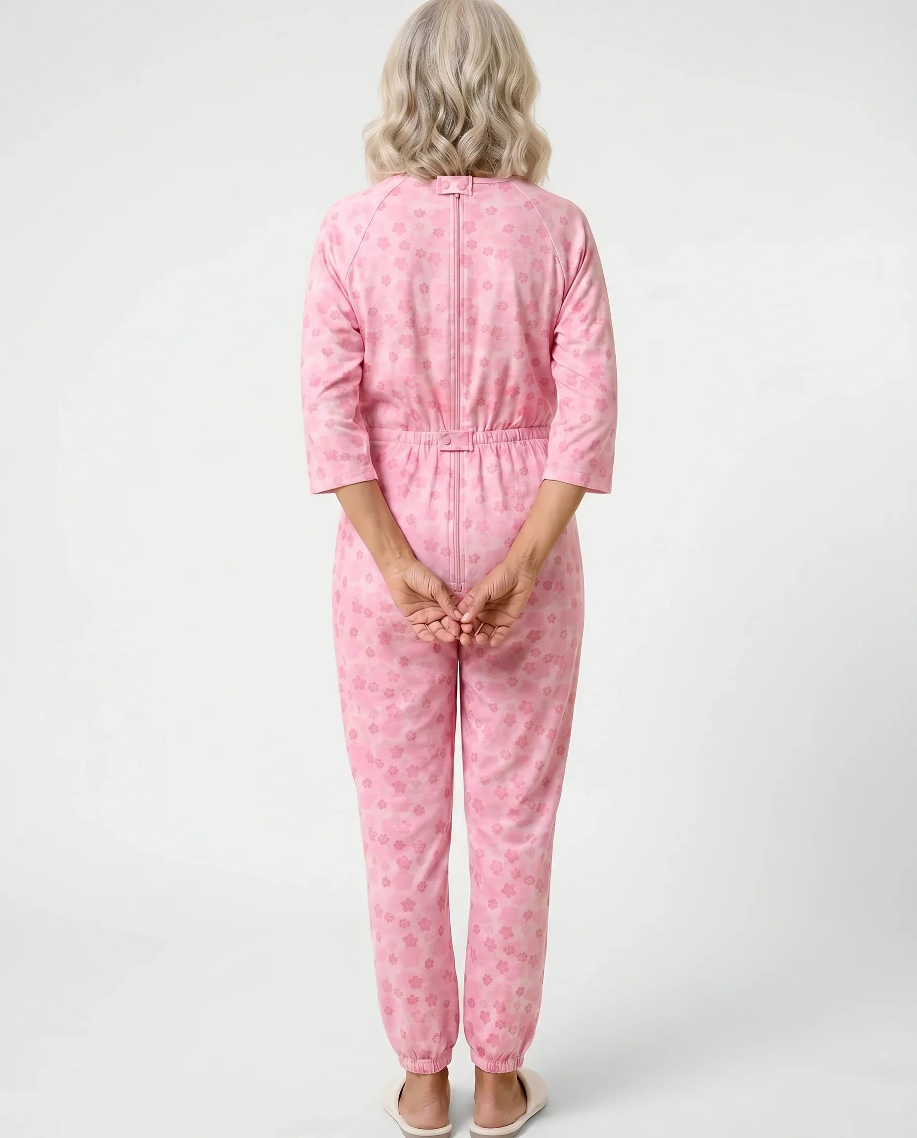 Senior woman wearing Ovidis adaptive Carrie Orchid jumpsuit, full body back view showing center-back zipper and snap closures