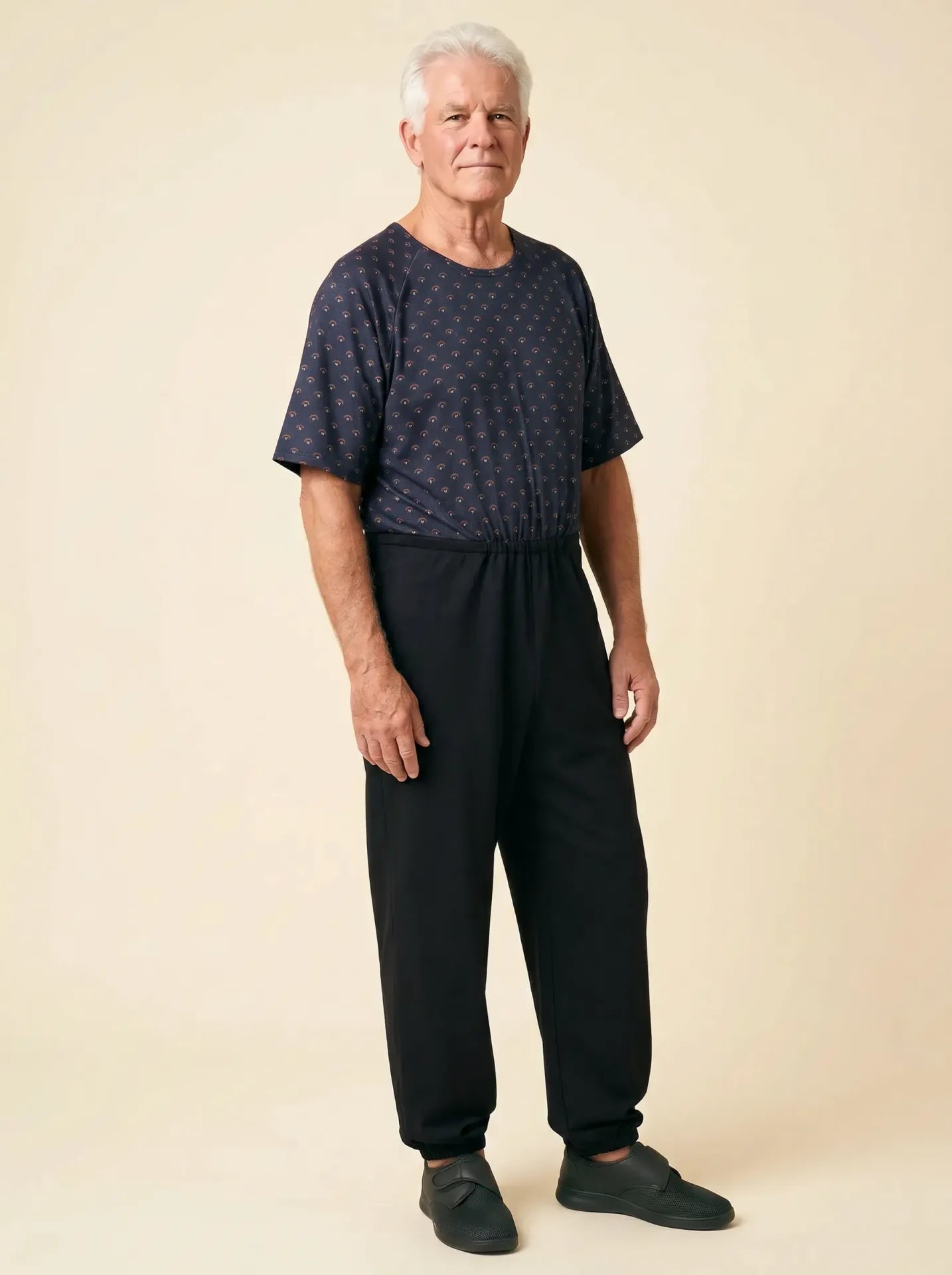 Senior man wearing Ovidis adaptive Bobby Copper jumpsuit, front view, warm studio lighting