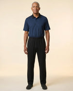 Senior man wearing Charly Twilight adaptive jumpsuit — deep midnight navy micro-pattern polo top with black pants