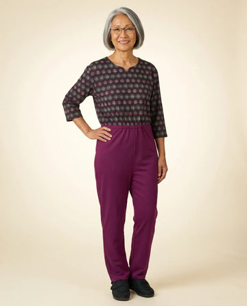 Senior woman wearing Ovidis adaptive Bella Dahlia jumpsuit — circle print top with magenta pants