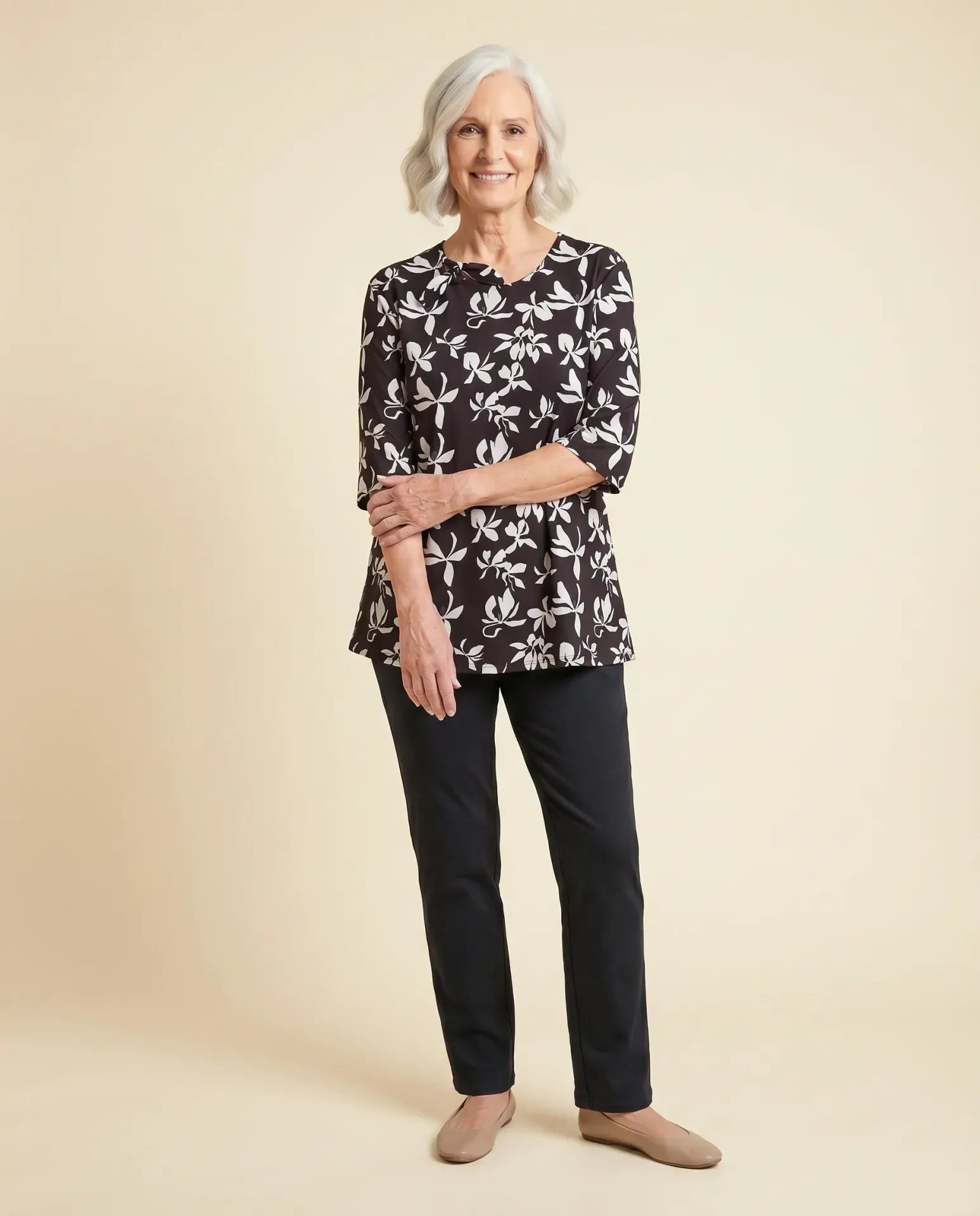 Senior woman wearing Ovidis adaptive black floral knit top with feminine sleeve detail, easy dressing