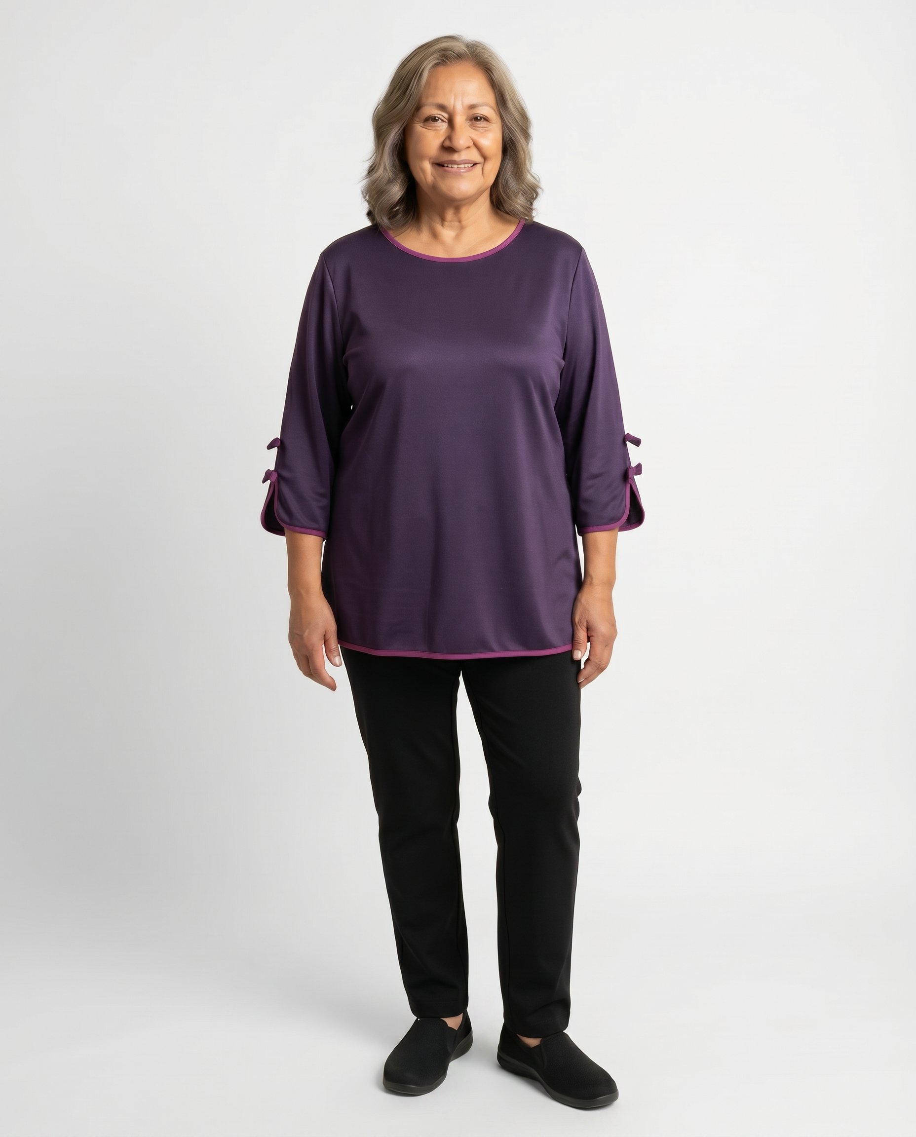 Senior woman wearing adaptive deep plum satin-effect top with sleeve bow-knot details and magenta piping trim