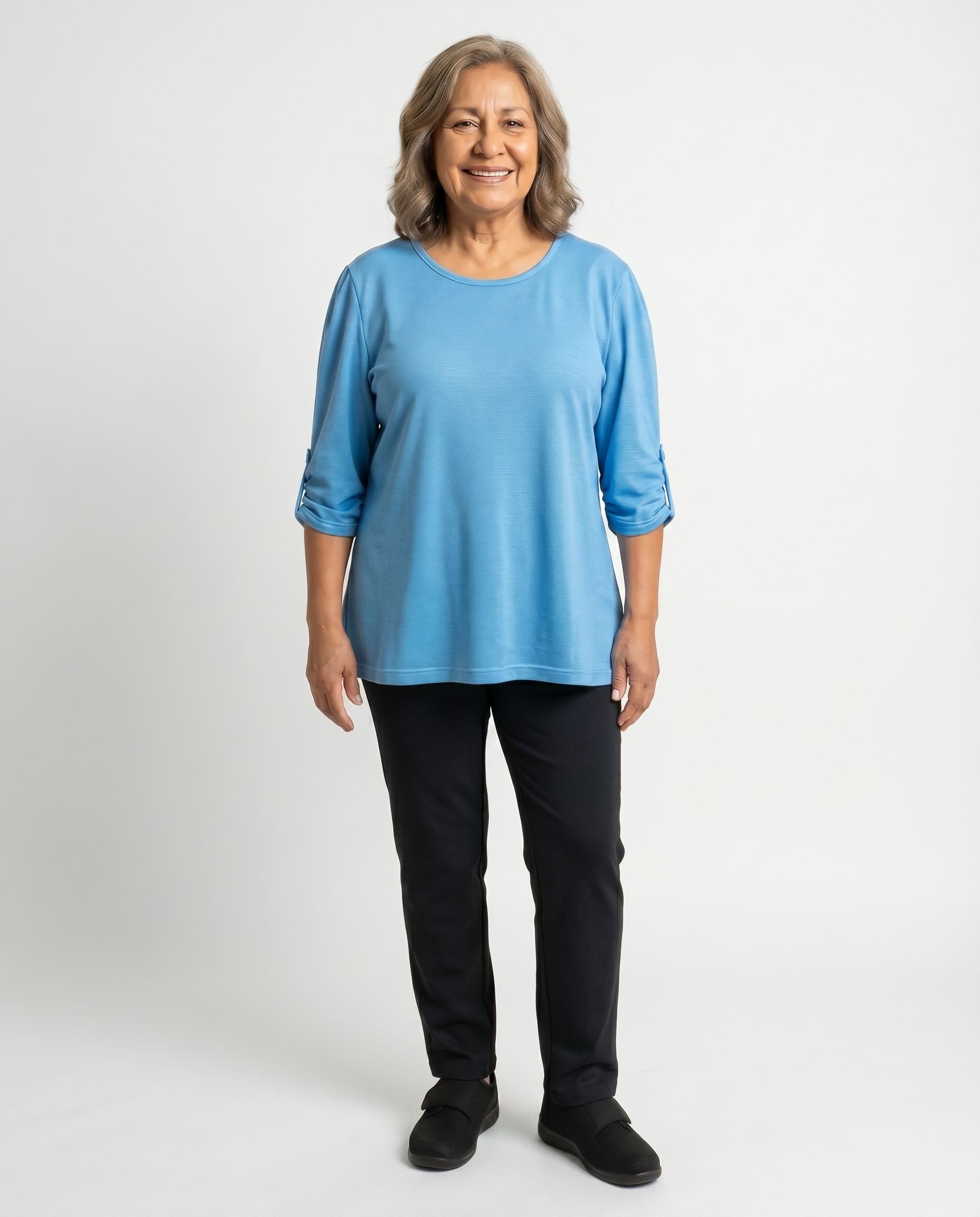 Senior woman wearing Ovidis adaptive blue micro pique top with shirred sleeve tab detail, easy dressing