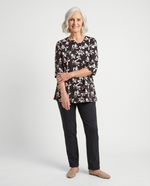Senior woman wearing Ovidis adaptive black floral knit top with feminine sleeve detail, easy dressing