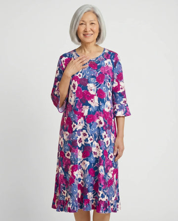 Senior woman wearing Romei Fushia adaptive floral dress with bell sleeves, front view