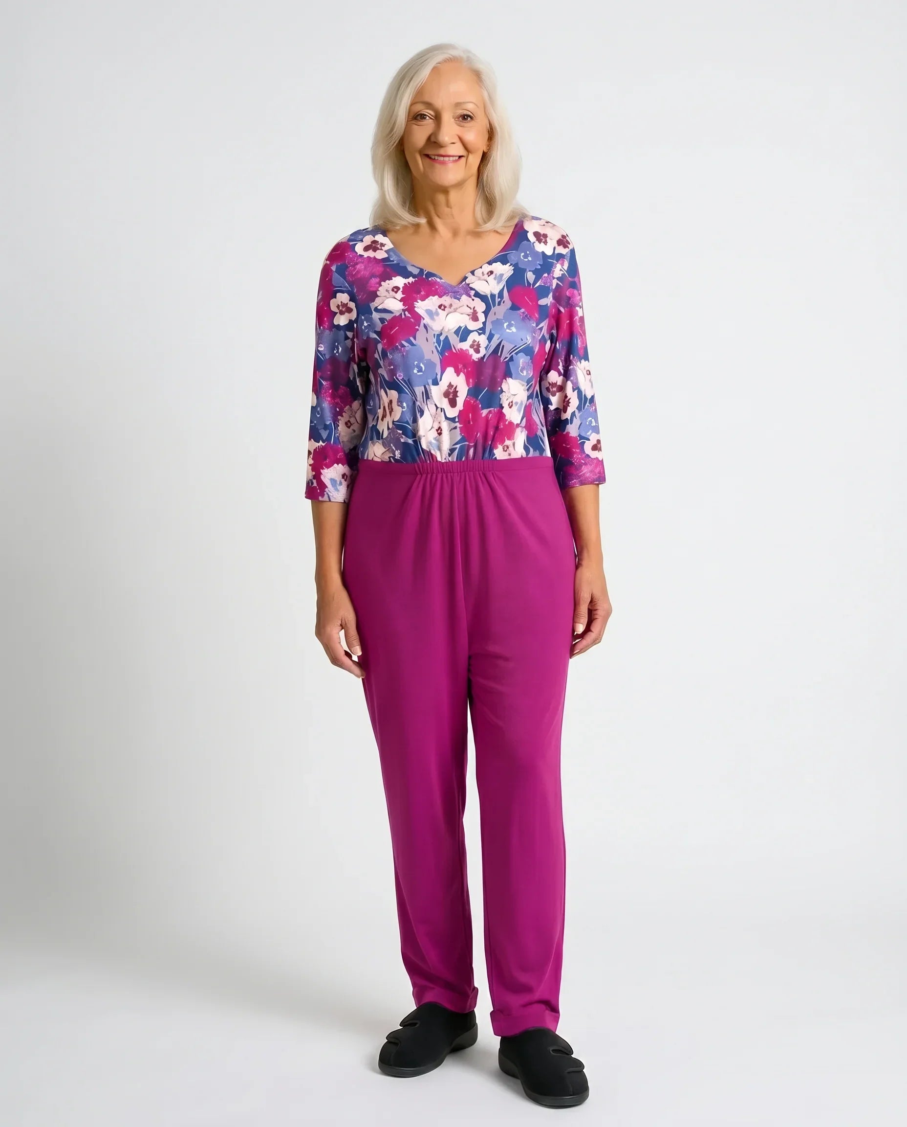 Senior woman wearing Ovidis Sia Fuchsia adaptive jumpsuit — floral print top with fuchsia pants, full body front view