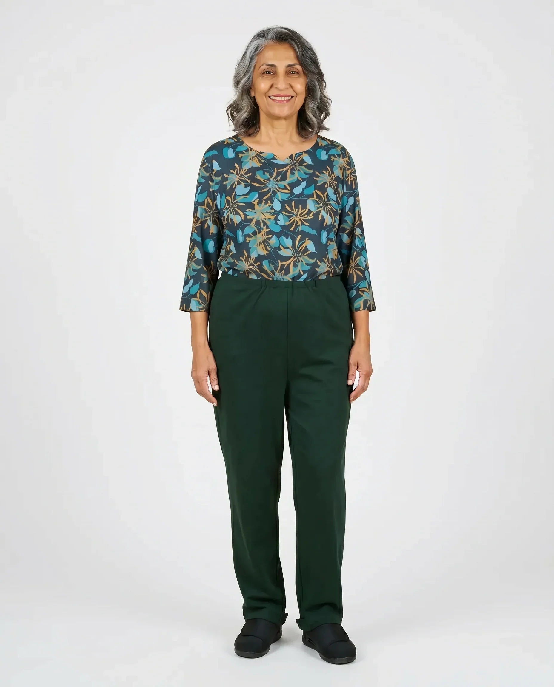 Senior woman wearing Ovidis adaptive Sia Greenery jumpsuit, full body front view
