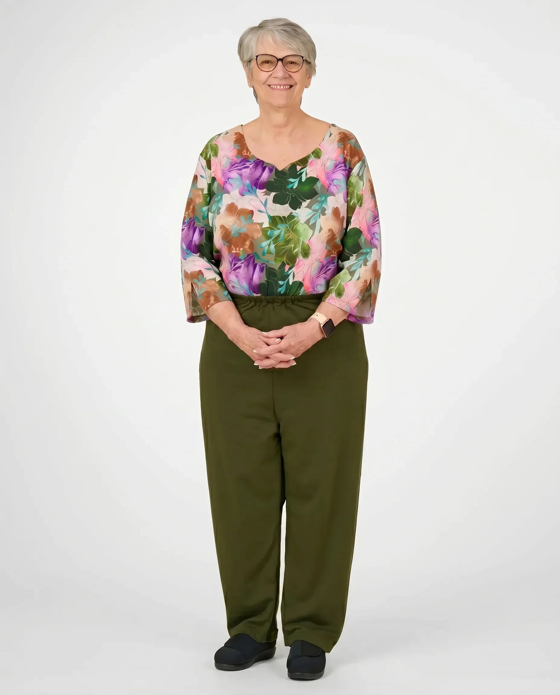 Senior woman wearing Ovidis adaptive Sia Olive jumpsuit, full body front view
