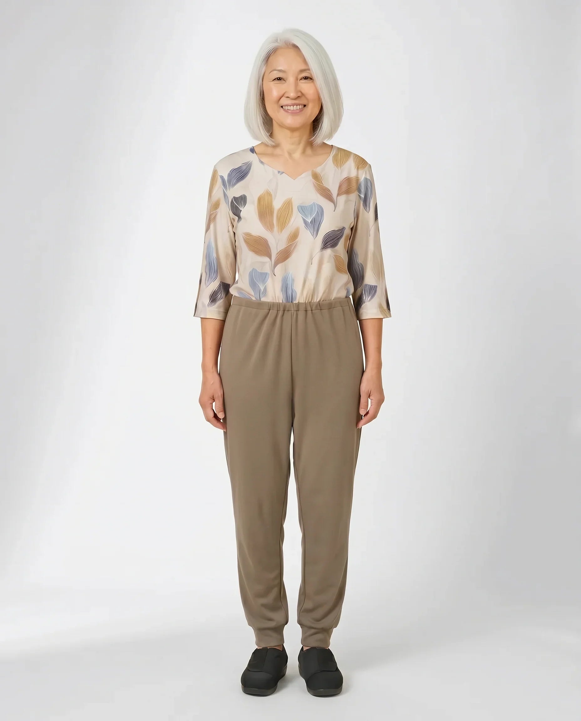 Senior woman wearing Ovidis adaptive Sia Tan jumpsuit, full body front view