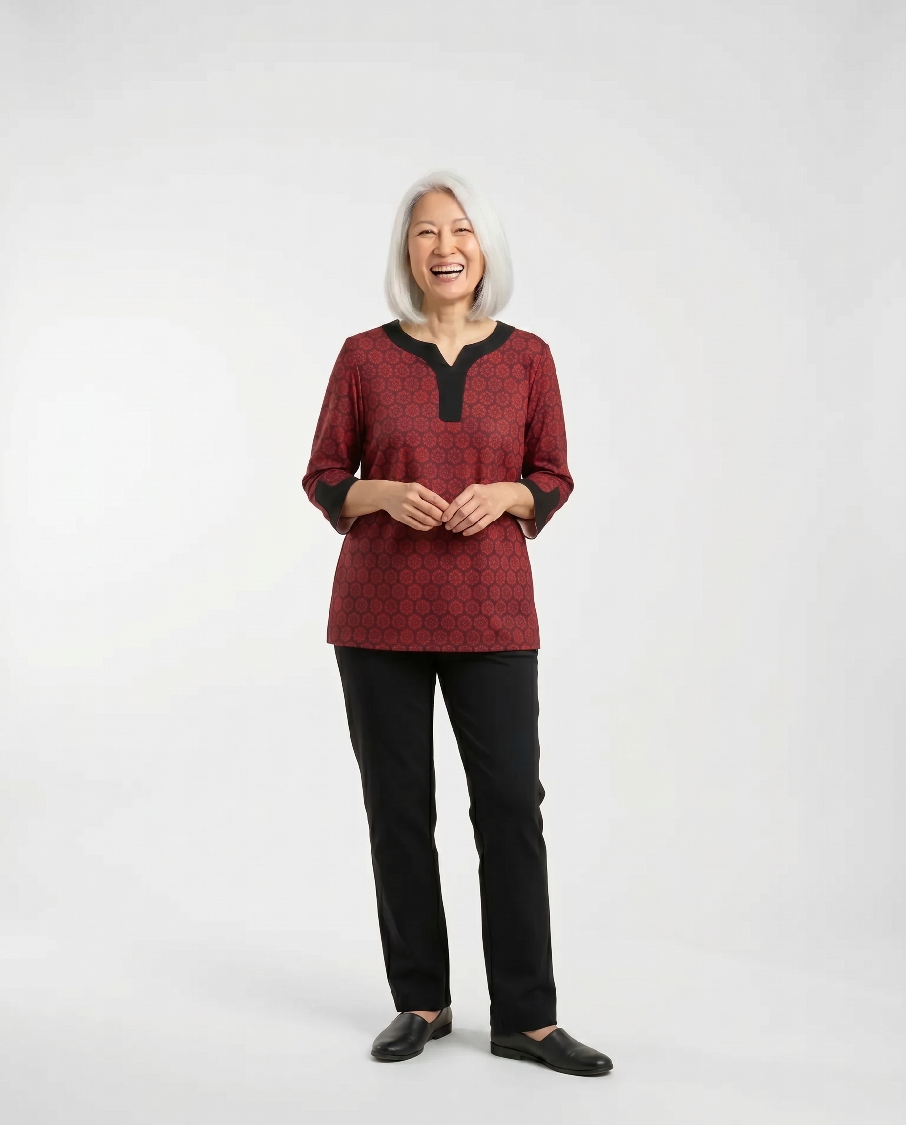 Senior woman wearing adaptive garnet red floral-print top with contrast black collar and sleeve trim, paired with black pants