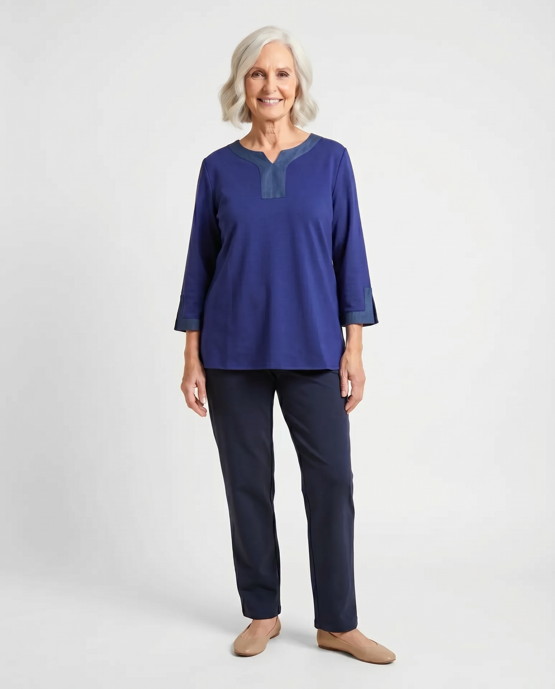 Senior woman wearing adaptive indigo blue top with contrast denim V-neckline and sleeve cuff trim, paired with navy pants